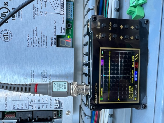IEI technician using a handheld commissioning tool to test a building automation controller communication loop